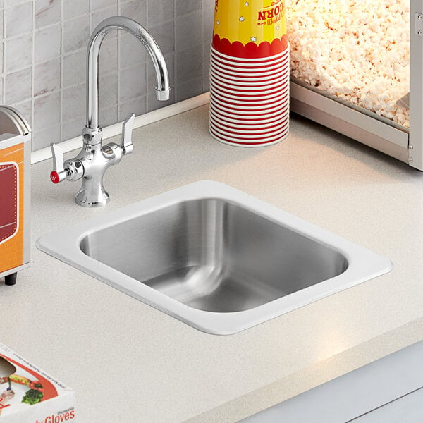 A Regency stainless steel drop-in sink in a kitchen with popcorn on the counter.