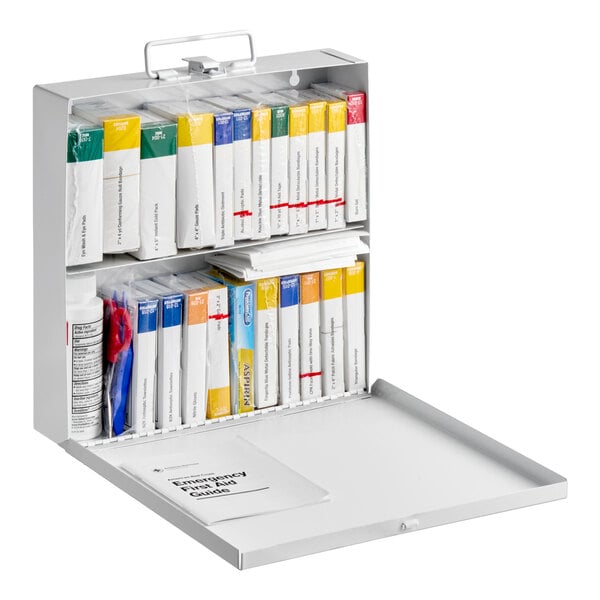 A metal first aid kit case containing various individually packaged medical supplies and an emergency first aid guide.