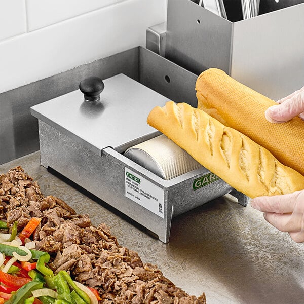 A person using a Garde cast aluminum butter spreader to cut bread.