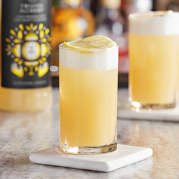 A glass of Twisted Alchemy lemon sour craft mixer with a lemon slice on top.