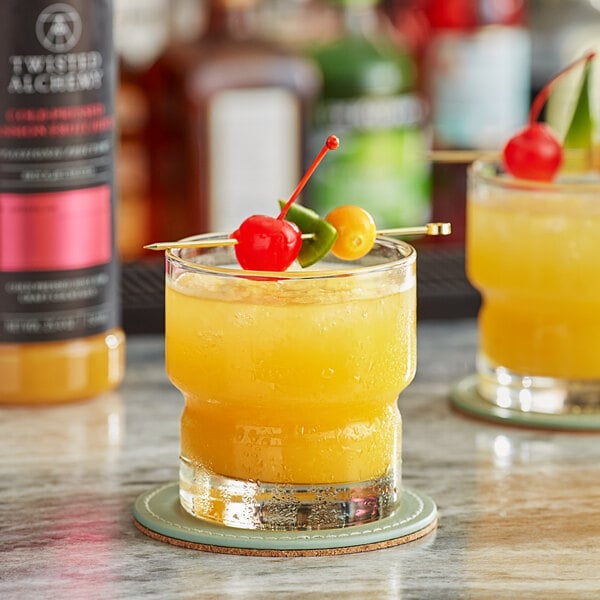 A table with a glass of yellow passion fruit juice with fruit on top and a glass of orange passion fruit juice with a cherry on top.