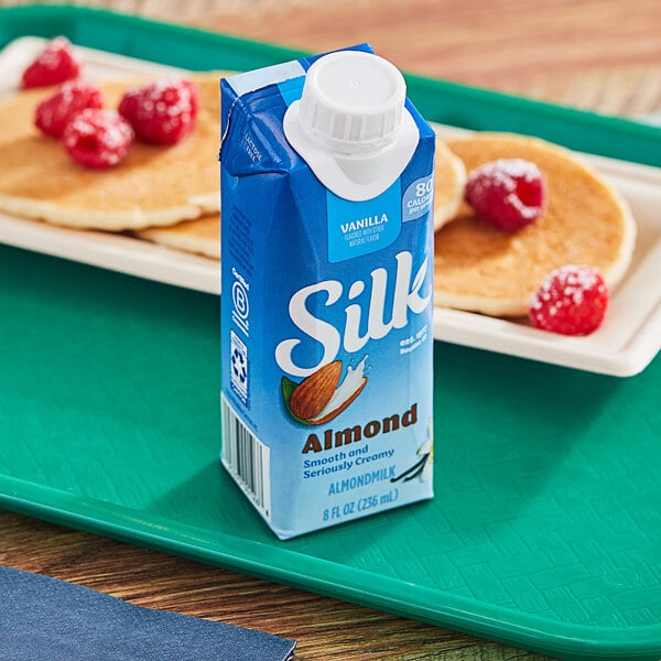 A blue carton of Silk Vanilla Almond Milk on a table with pancakes.