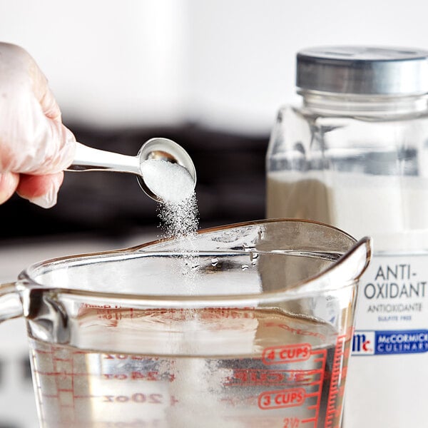 A hand holding a spoon full of McCormick Culinary Anti-Oxidant powder.