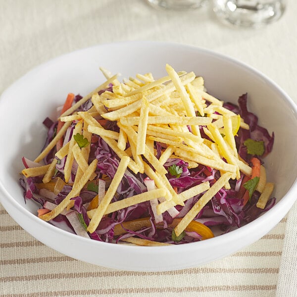A bowl of French's Potato Sticks on a table with other food.
