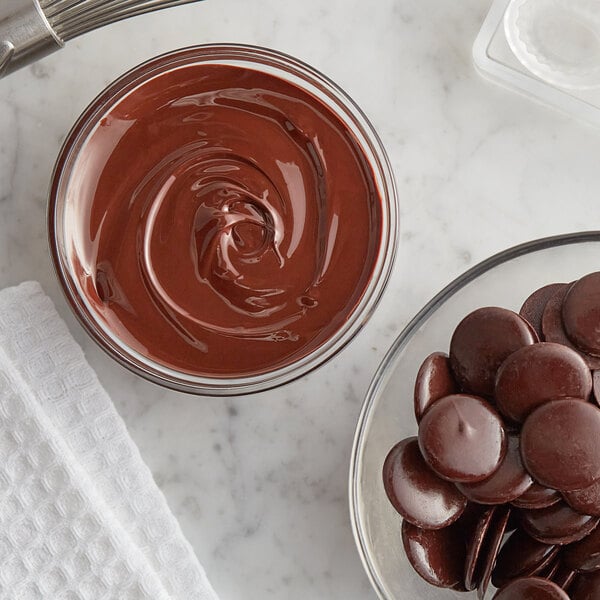 A bowl of chocolate spread with chocolate chips and chocolate buttons.