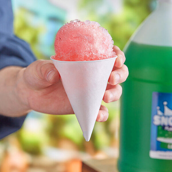 A hand holding a Choice white paper cone filled with a pink snow cone.