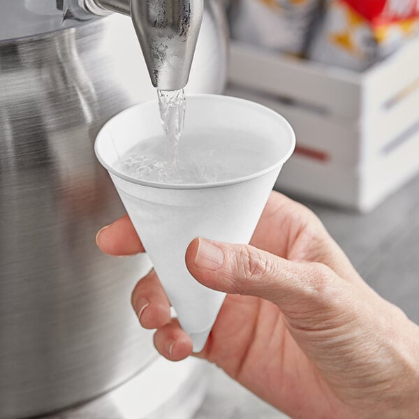 A hand holding a Choice white paper cone with water pouring into it.