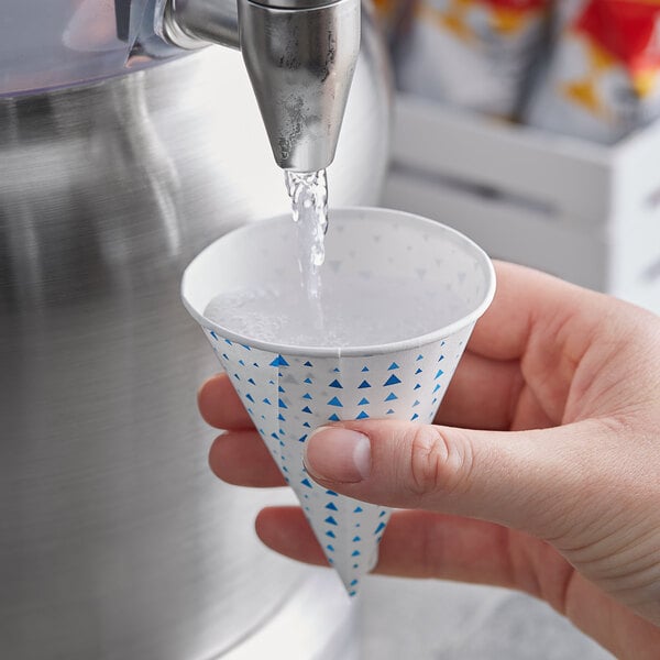 A hand holding a Choice paper cone with water pouring out of it.