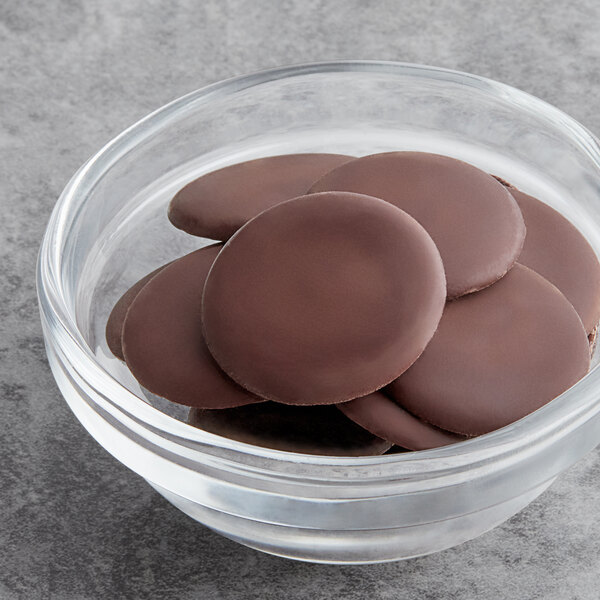 A glass bowl of Republica del Cacao dark chocolate couverture with chocolate covered cookies.