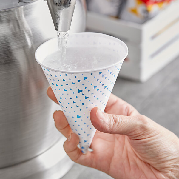 A hand pouring water into a Choice paper cone cup.