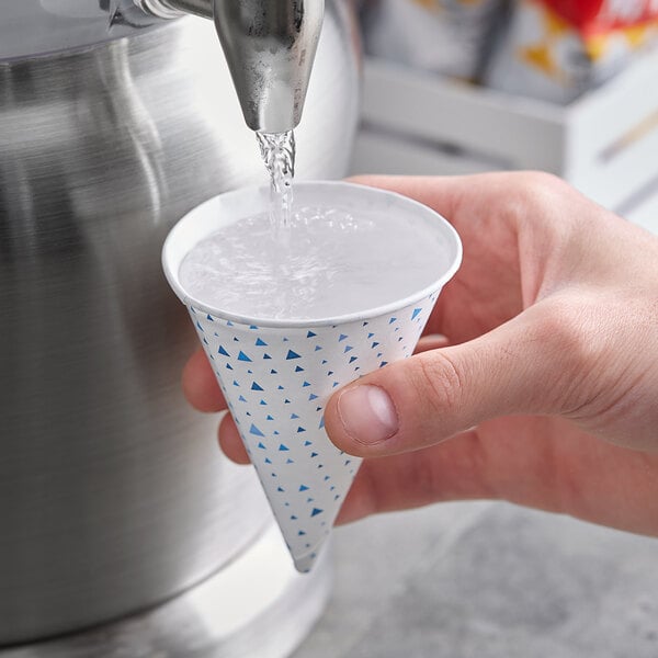 A hand pouring water from a funnel into a Choice paper cone cup.