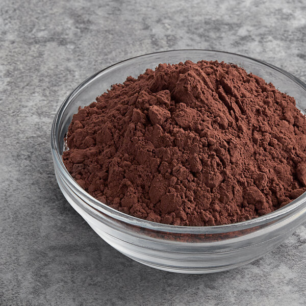 A bowl of Valrhona Dutched cocoa powder on a gray surface.