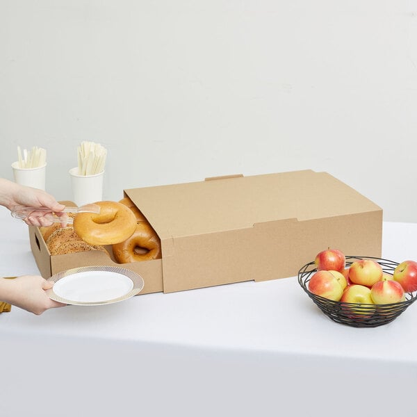 A person holding a Sabert large plastic catering tray with a cover full of food.