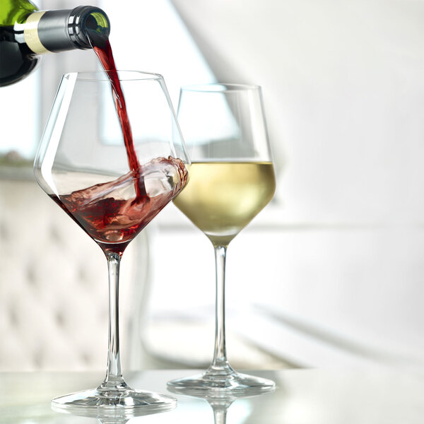 A close-up of a Stolzle Revolution burgundy wine glass filled with red wine.