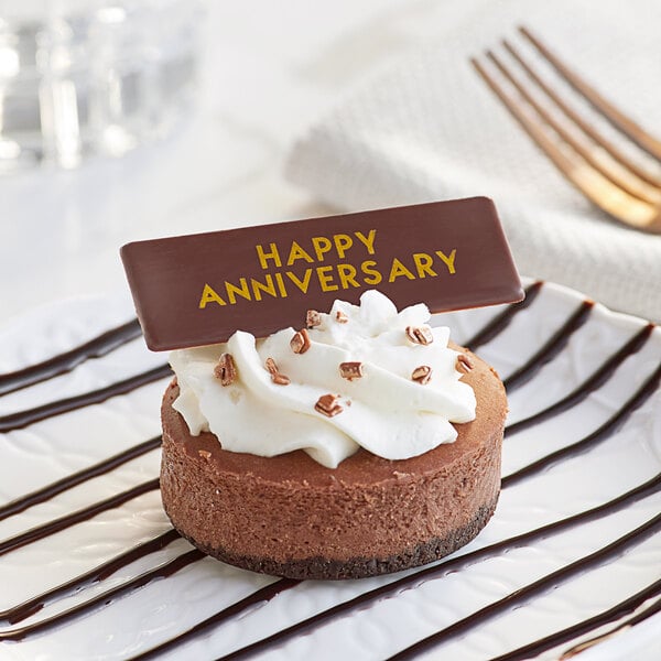 A chocolate cake with a Chocolatree Happy Anniversary chocolate decoration on top.