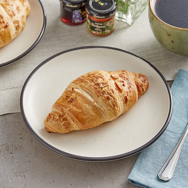 A plate with a croissant and a plate with croissants on a table with a cup of coffee.