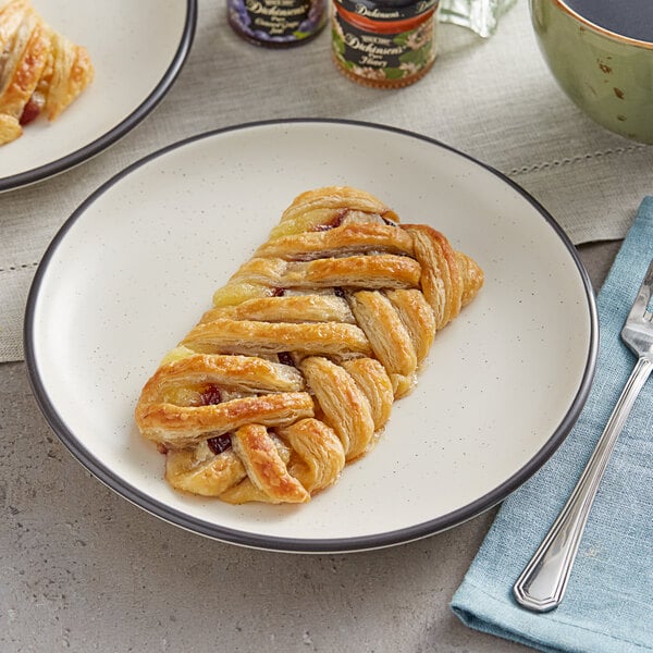 Two plates with blueberry custard braided danishes on them on a table in a bakery display.