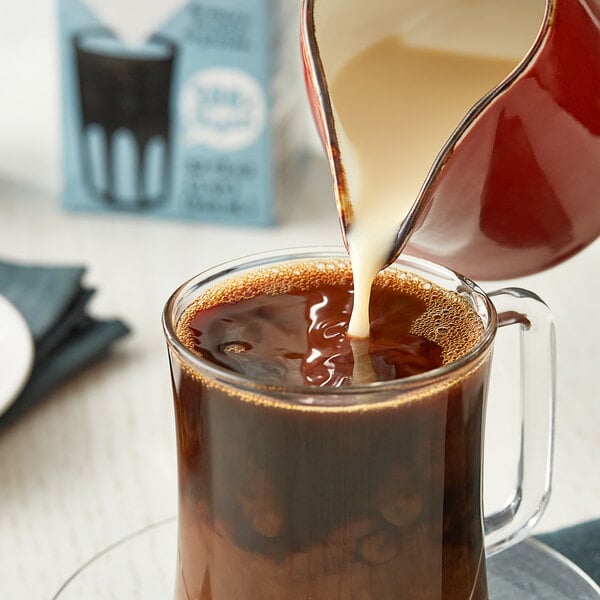 Oatly Original Oat Milk being poured into a glass of coffee.