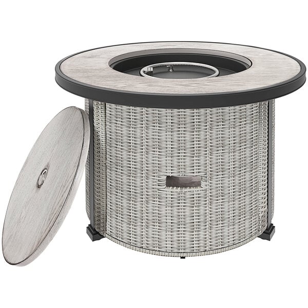 A 36" round stainless steel fire pit on a table with a lid.