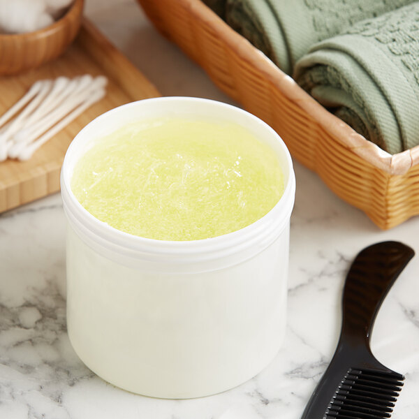 A white container of yellow liquid next to a black comb and towels.