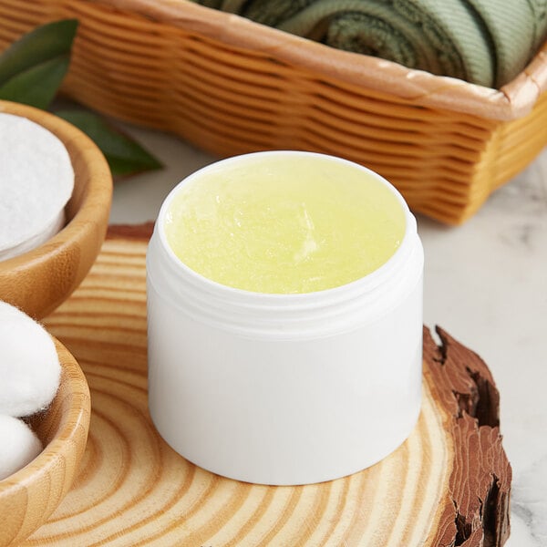 A white customizable jar filled with yellow liquid next to a basket of cotton.