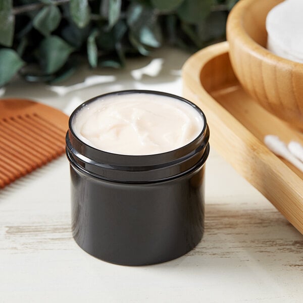 A black container of cream on a wooden surface.