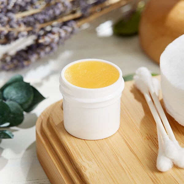 A white container with a yellow substance in it on a wooden surface.