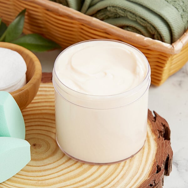 A 12 oz. clear polystyrene jar of white cream on a wood surface.
