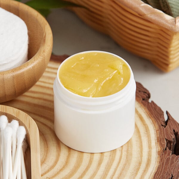 A white Thick Wall Plastic Jar filled with yellow liquid next to a bowl of cotton buds.