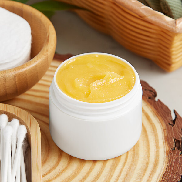 A white customizable jar filled with yellow liquid on a wood surface.