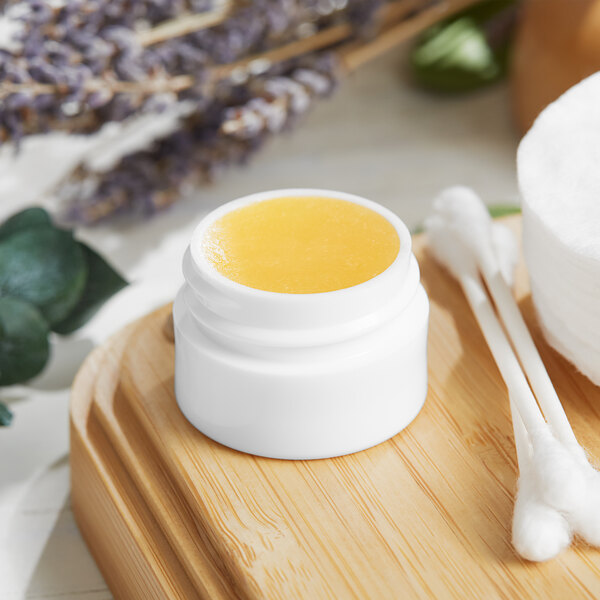 A white Thick Wall Polypropylene jar filled with yellow liquid on a wooden surface.