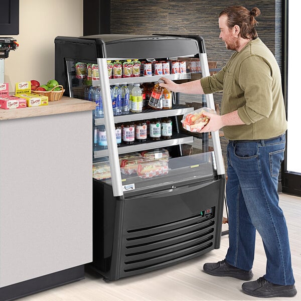 A man standing in front of an Avantco vertical air curtain merchandiser.