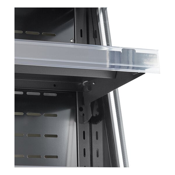 A shelf with a clear plastic tray on it inside a black vertical air curtain merchandiser.