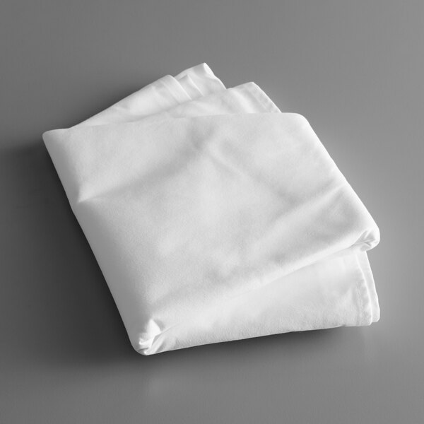 A folded Intedge white poly cotton blend tablecloth on a gray surface.