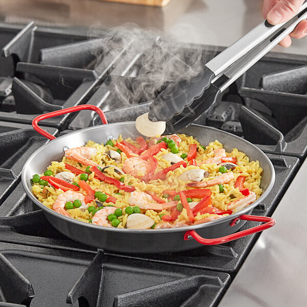 A person cooking shrimp and rice in a Vigor carbon steel paella pan.