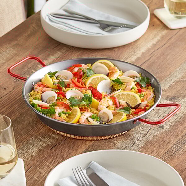 A Vigor paella pan of seafood with lemons and rice on a table.