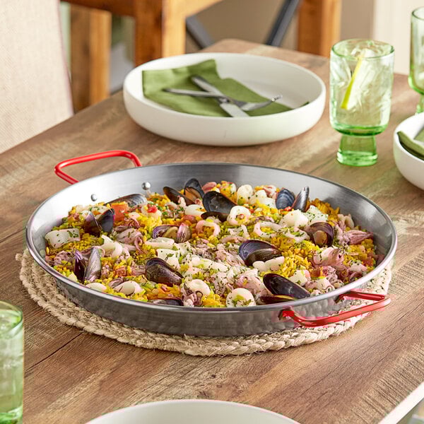 A Vigor 14" Paella Pan of seafood rice on a table.