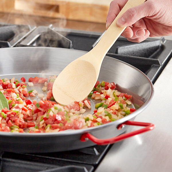 A person stirring food in a Vigor paella pan.