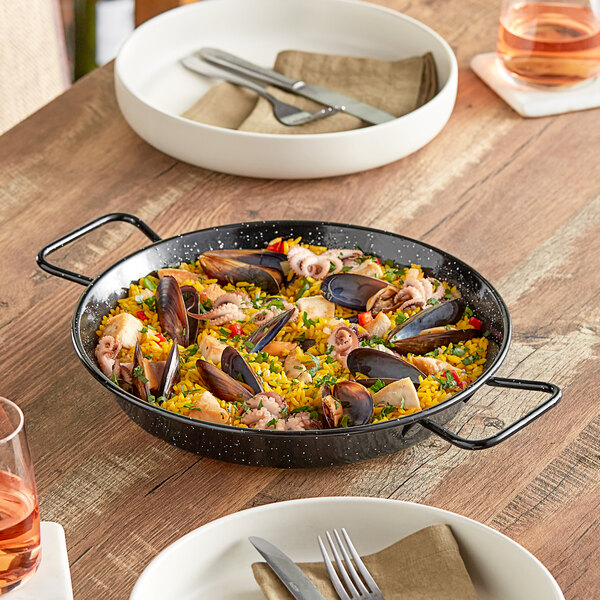 A Vigor enameled carbon steel paella pan filled with seafood rice on a table.