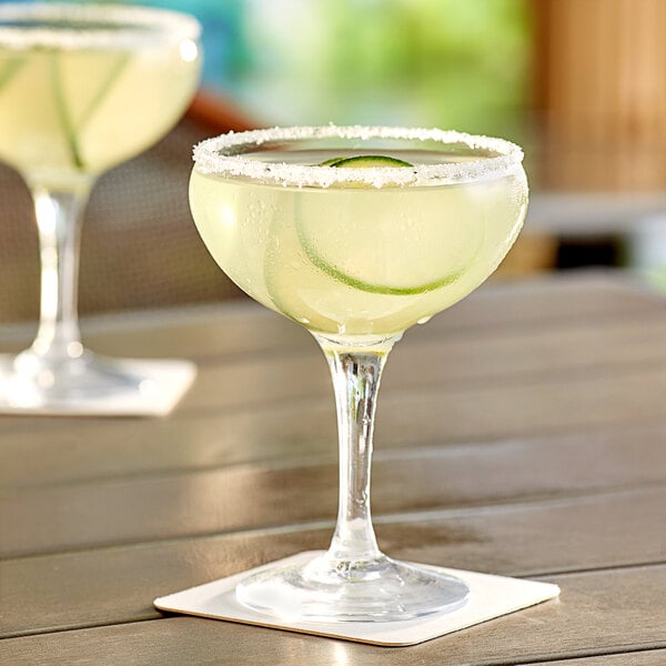 Two Acopa margarita glasses filled with drinks on a table.