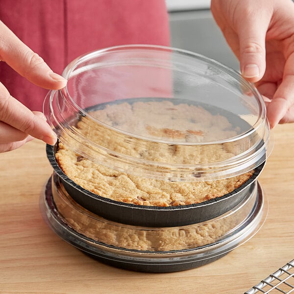 A person holding a Solut clear plastic lid on a container with food in it.