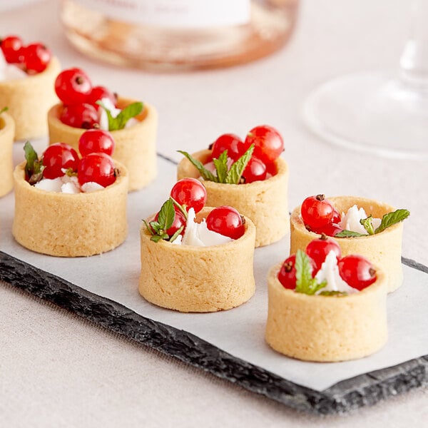 A group of La Rose Noire mini round vanilla tart shells filled with red berries.