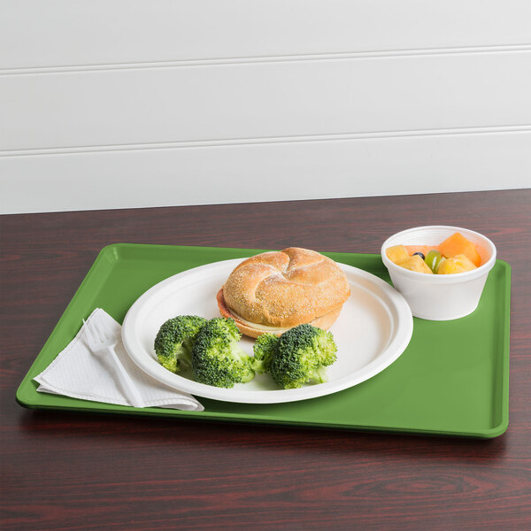 A Cambro lime-ade dietary tray with a sandwich, broccoli, and fruit on it.
