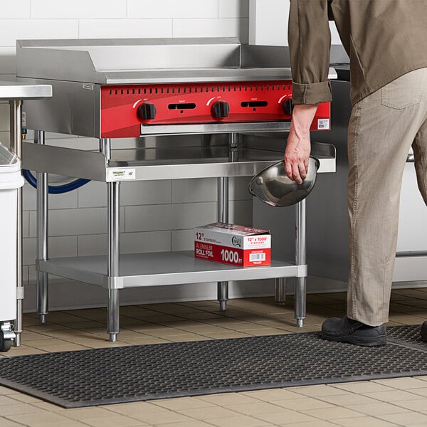 A person holding a pan over a stainless steel equipment stand.