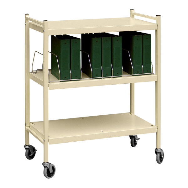 An Omnimed beige open cart with green binders on it.