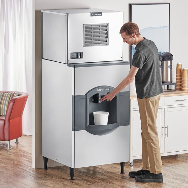 A man using a Scotsman air cooled ice machine to fill a cup with ice.