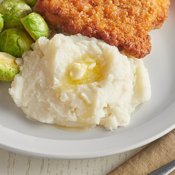 A plate with Honest Earth Creamy mashed potatoes, brussels sprouts, and fried chicken.