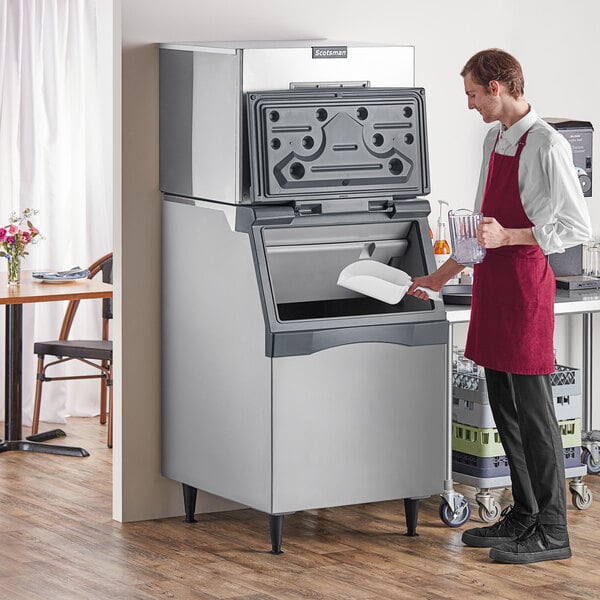 A man in a red apron using a Scotsman air cooled ice machine to fill a glass.