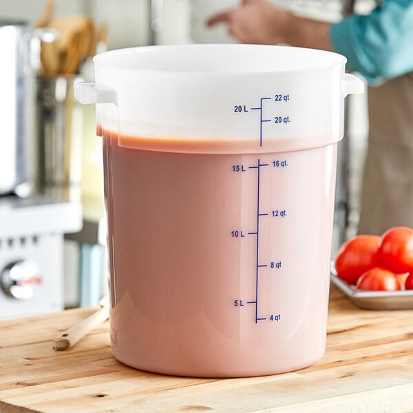 A white Carlisle food storage container with blue liquid and tomatoes inside.