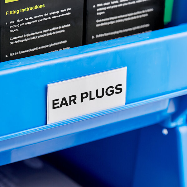 A blue plastic shelf with black and white labels in a black sign holder.